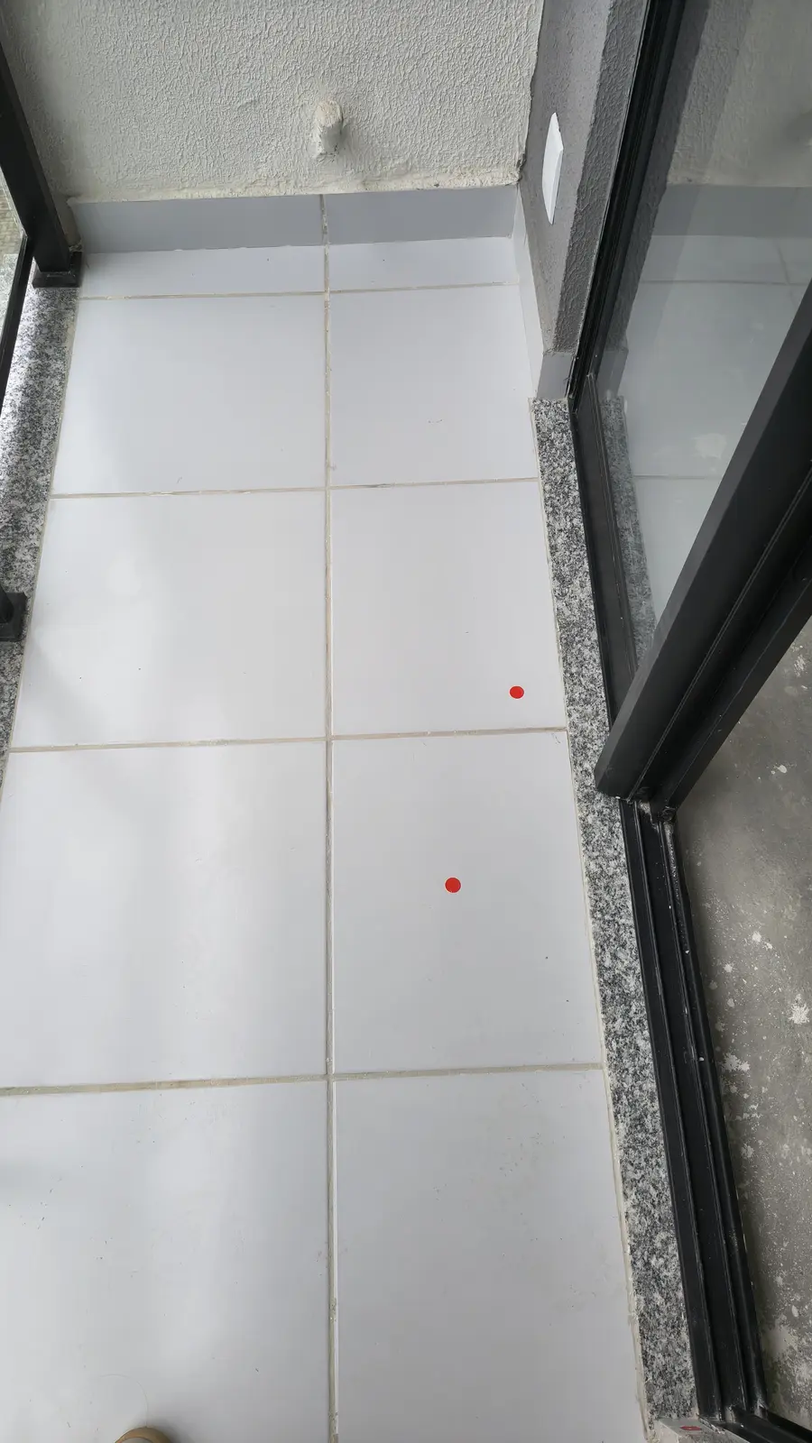 Marcações técnicas realizadas no piso de uma varanda durante vistoria de entrega de chaves